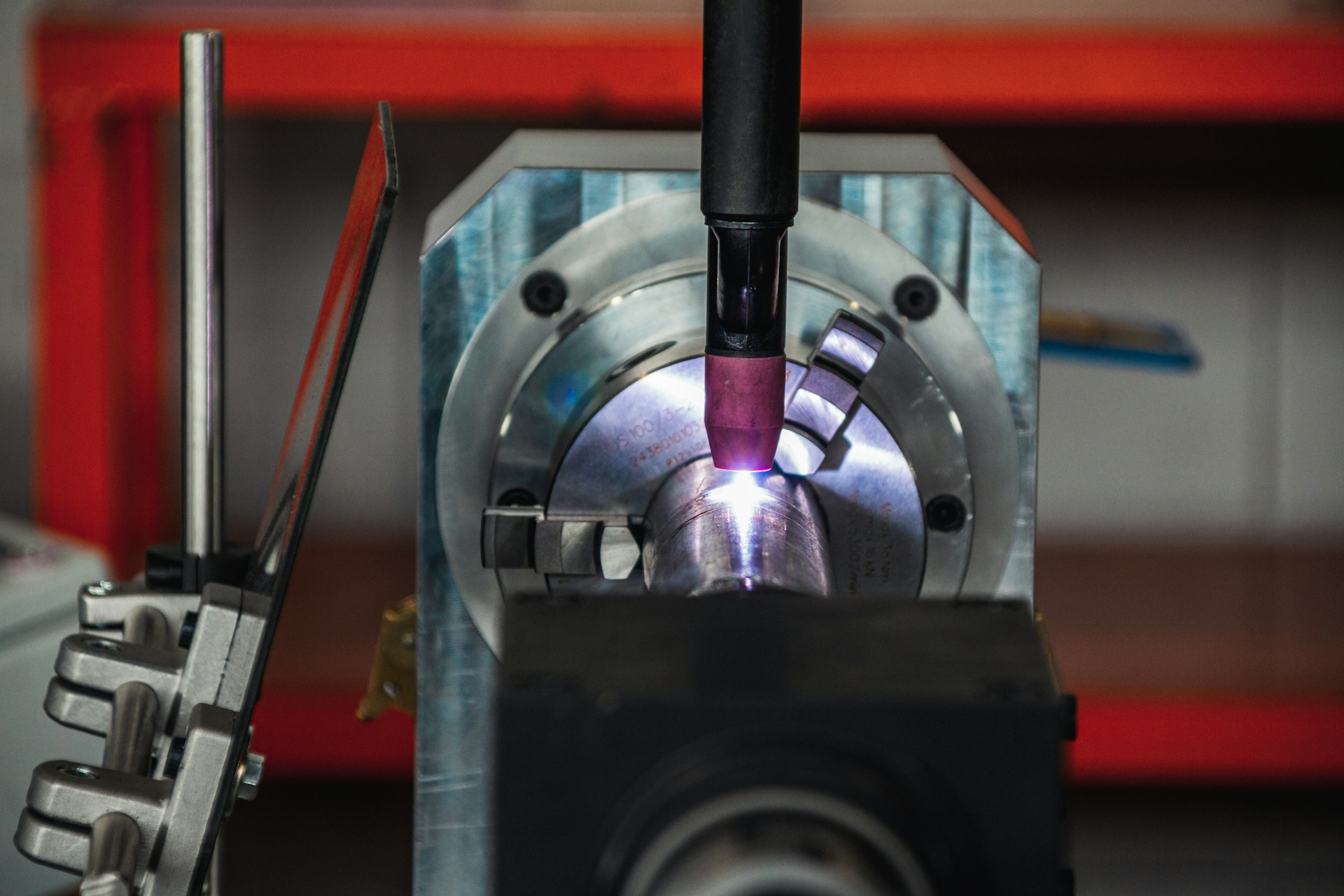 Ein CO₂-Laser bearbeitet eine Welle. Das kleine Schutzglas links schützt nur den Bediener.