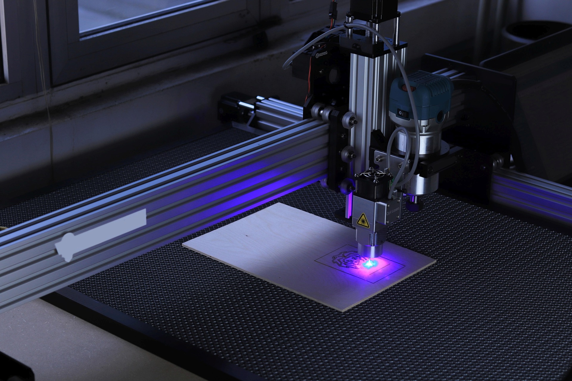 Ein CO2-Laser hinter Schutzglas wird an einem Plotter zum Lasergravieren eingesetzt.